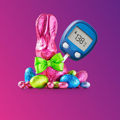 Schokoladen-Osterhase mit weiteren Schokoeiern und einem Diabetes-Messgerät