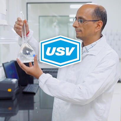 USV-Logo vor dem Bild eines Mannes in weißem Kitte, der ein Reagenzglas in der Hand hält.