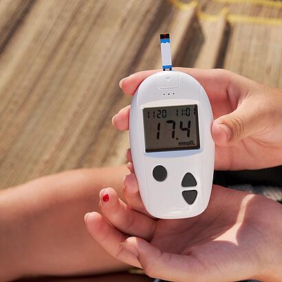 Diabetes-Messgeraet neben einem blutigen Finger 