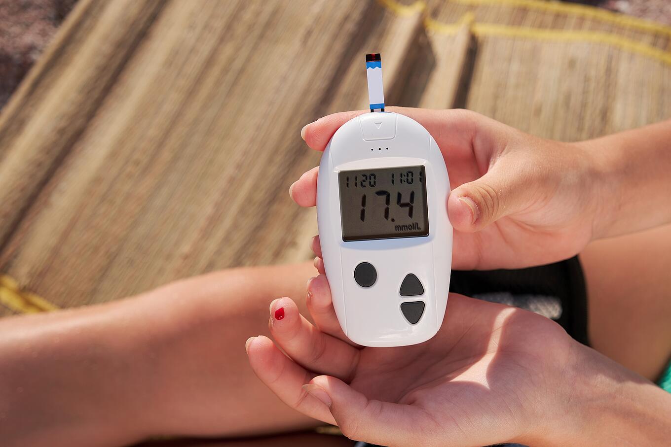 Diabetes-Messgeraet neben einem blutigen Finger 