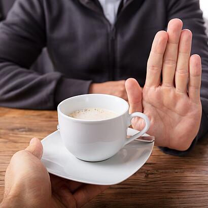 Ablehnende Handbewegung bei einer angebotenen Tasse Kaffee