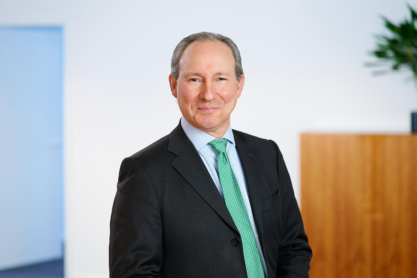 Portrait eines Juta-Pharma-Mitarbeiters. Er trägt ein blaues Hemd, eine grüne Krawatte und ein schwarzes Jackett.