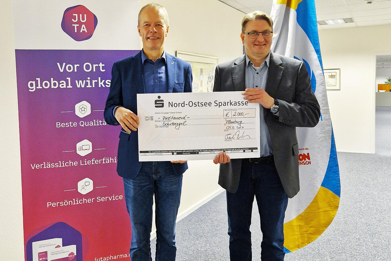 Juta-Pharma-Geschäftsführer Torben Jung Laursen und Schutzengel-Geschäftsführer Volker Syring halten einen großen symbolischen Check über 2.000 Euro für Schutzengel.