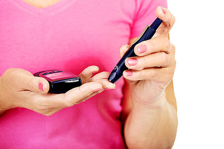 Frau misst Blutzucker am Finger.