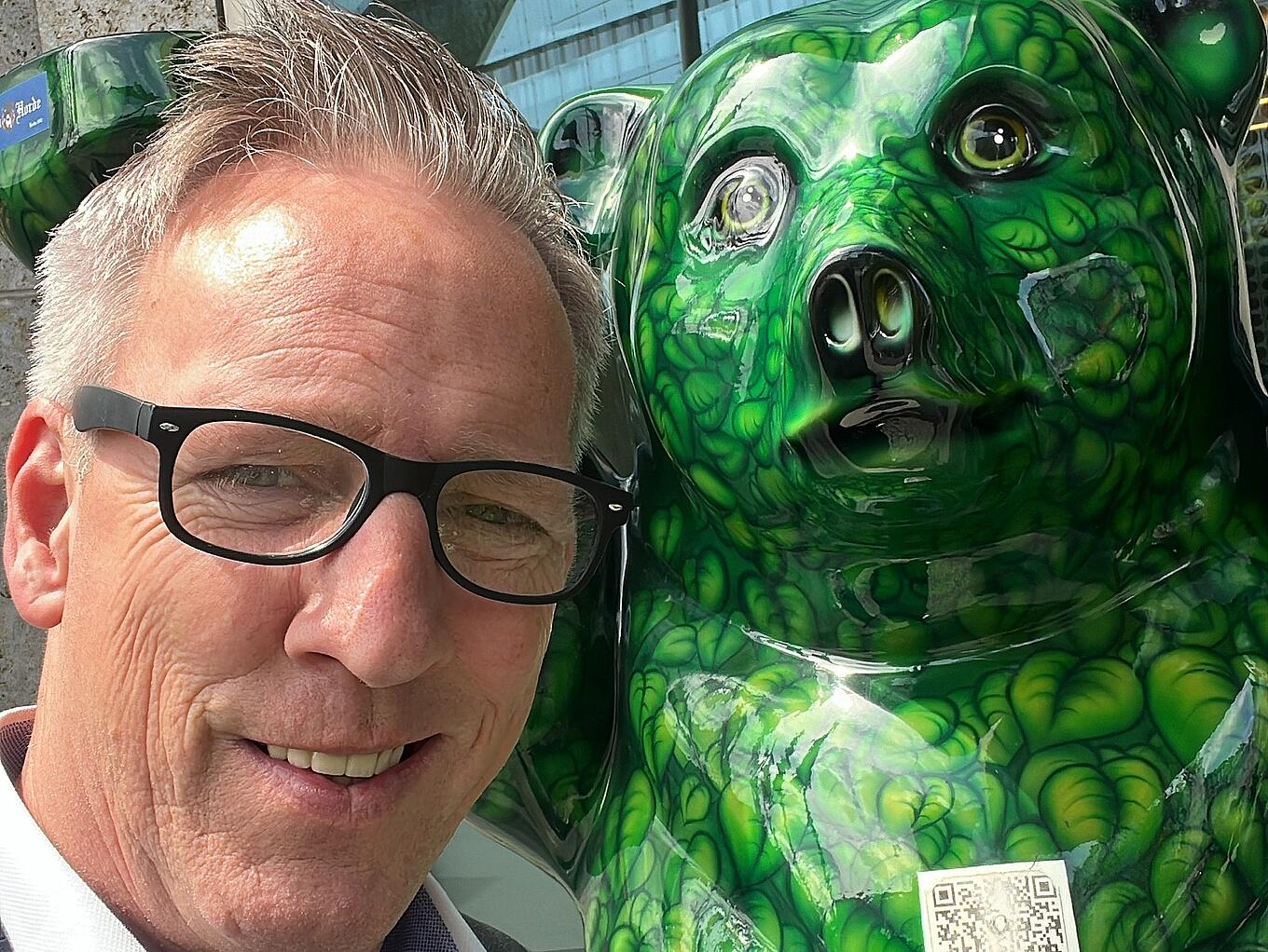 Marco Kunk von Juta Pharma neben einer grünen Figur des Berliner Bären.