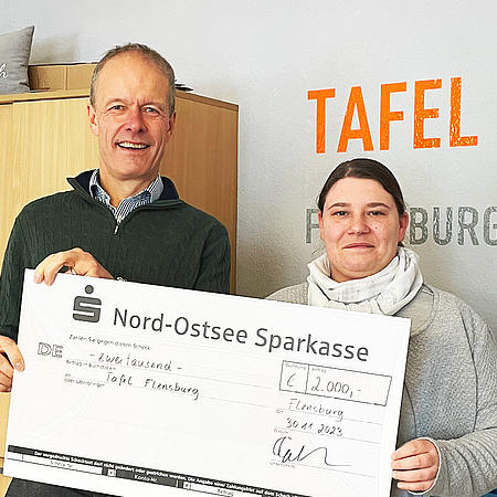 Juta-Pharma-Geschäftsführer Torben Jung Laursen überreicht einen symbolischen Check an die Leiterin der Tafel Flensburg.