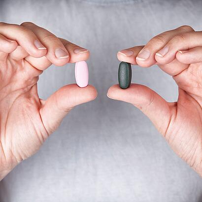 Zwei Hände zeigen zwei unterschiedliche farbende Tabletten