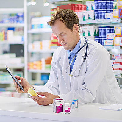 Apotheker am Tresen mit verschiedenen Medikamenten